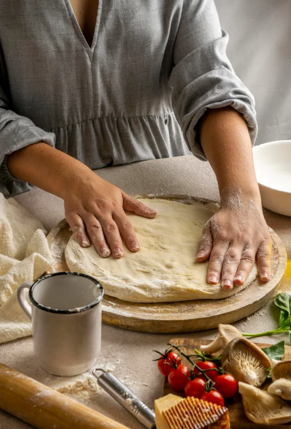 Manos estirando la masa de pizza artesanal